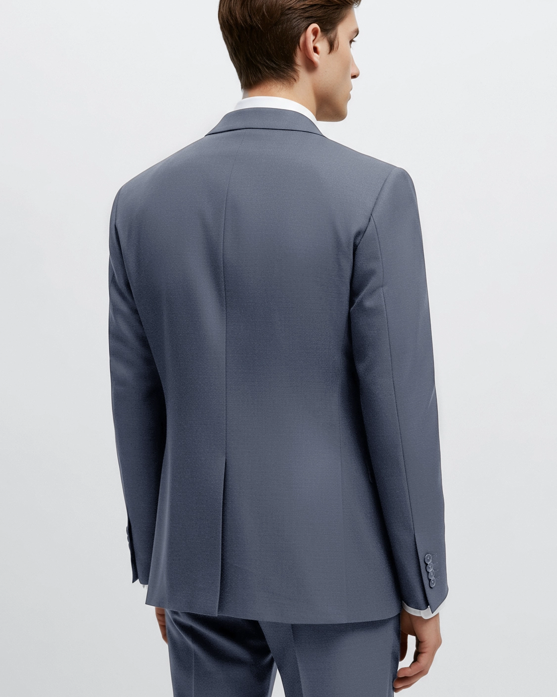 Rear view of man in a tailored gray suit, showing jacket details and elegant styling, against a light background.