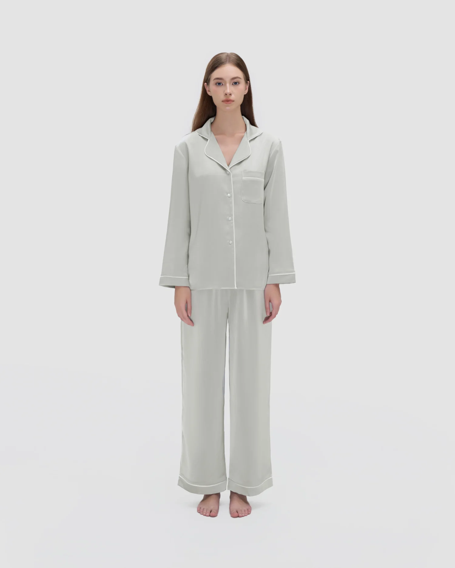 Woman wearing light gray ROSIE HONG silk pajamas standing on a white background.