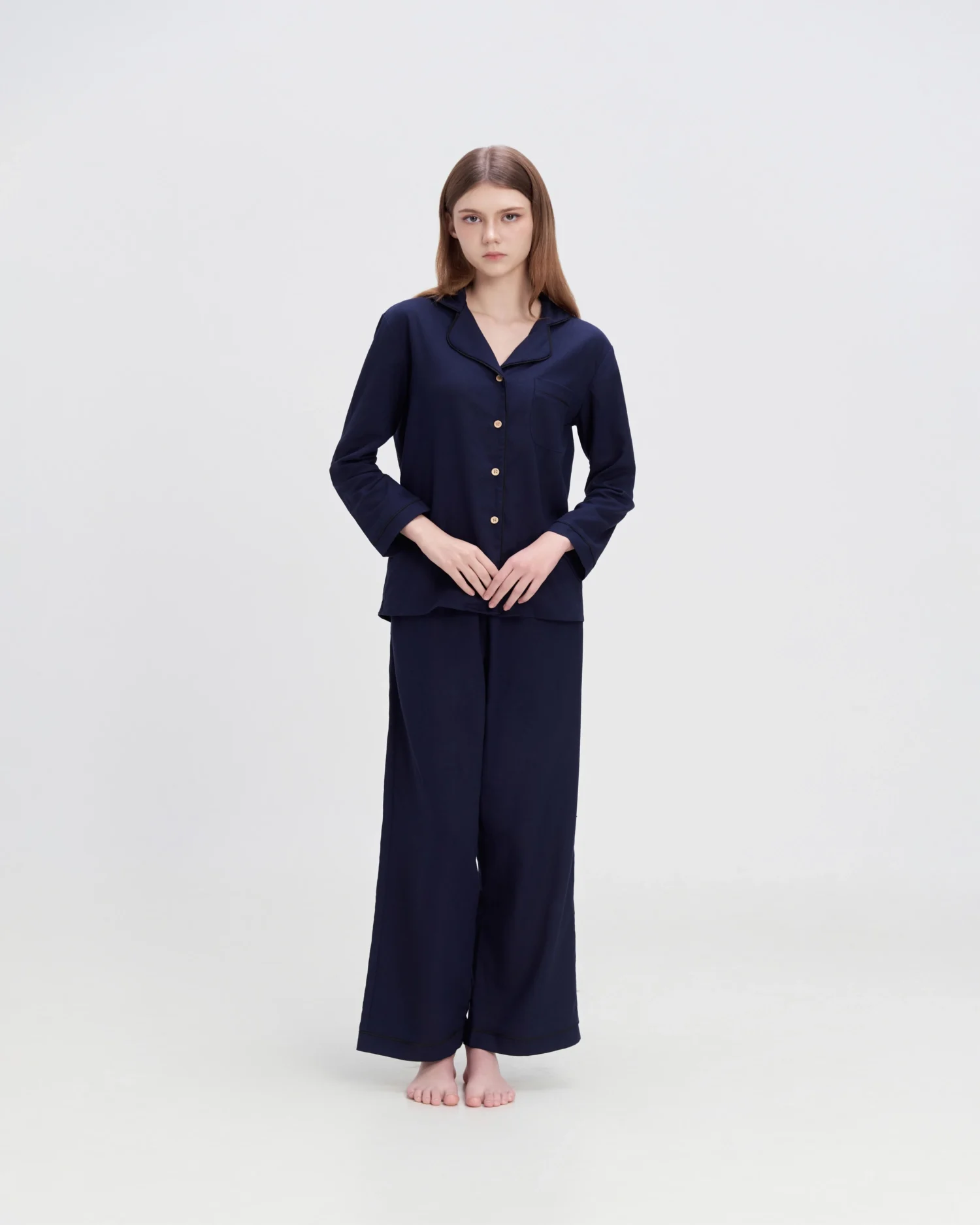 Woman in ROSIE HONG navy pajamas standing on a white background, showcasing comfortable and stylish sleepwear.