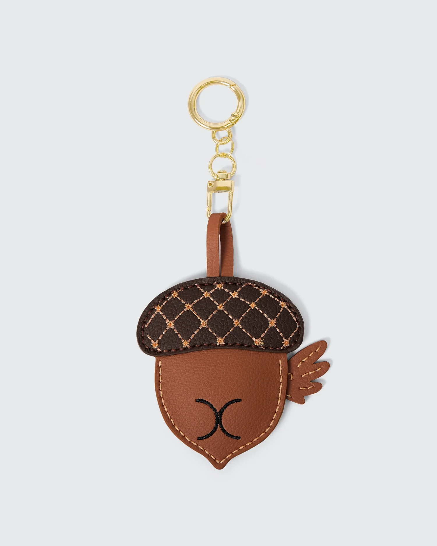 Acorn-shaped vegan leather keychain with gold ring and embroidered details on white background.