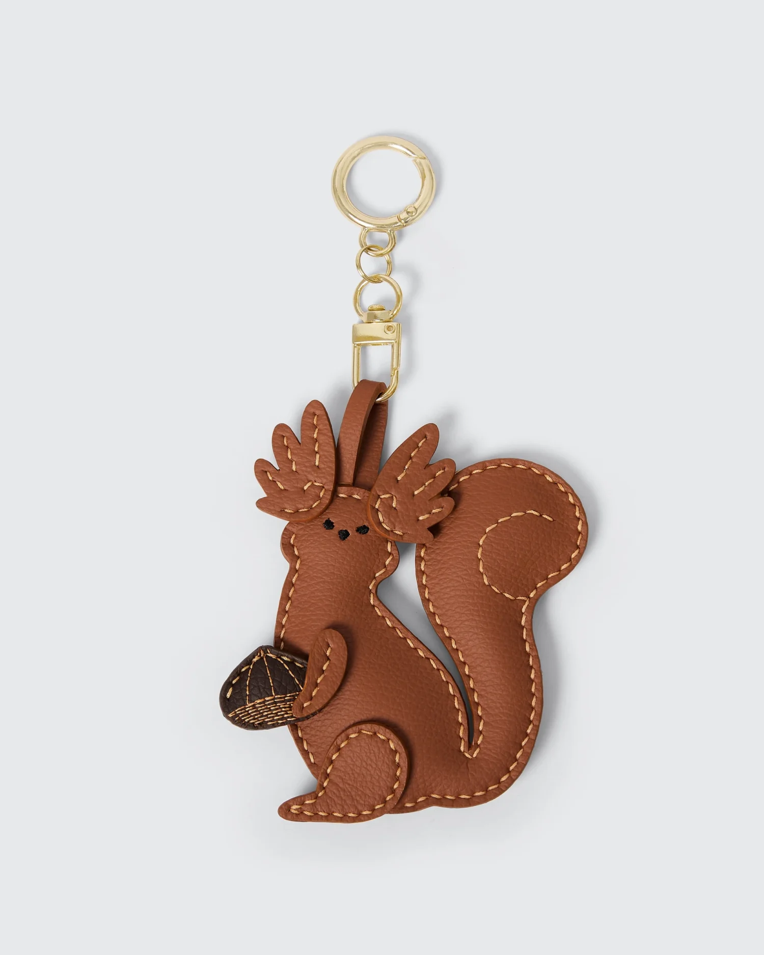 Cute vegan leather squirrel keychain with detailed stitching, holding an acorn. Perfect accessory for bags and keys.