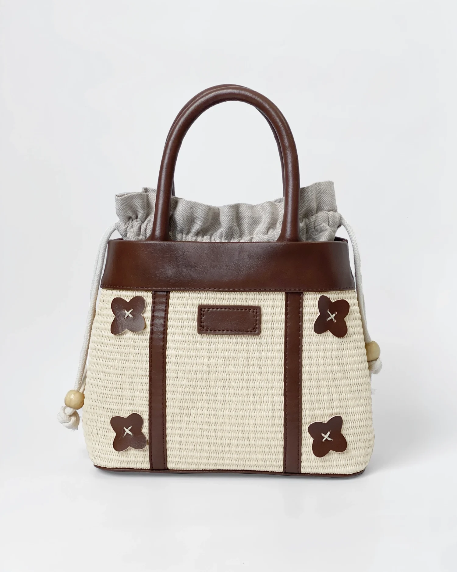 Elegant ROSIE HONG woven handbag with brown leather trim and floral accents on a white background.