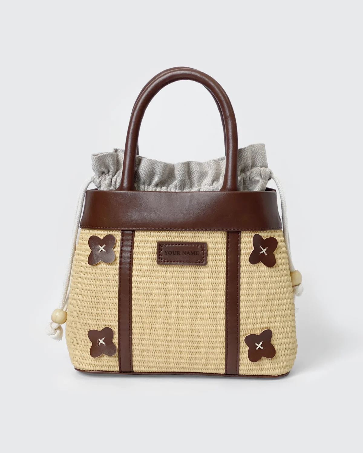 Elegant straw and leather handbag with floral accents and drawstring closure on display. Ideal for casual outings.