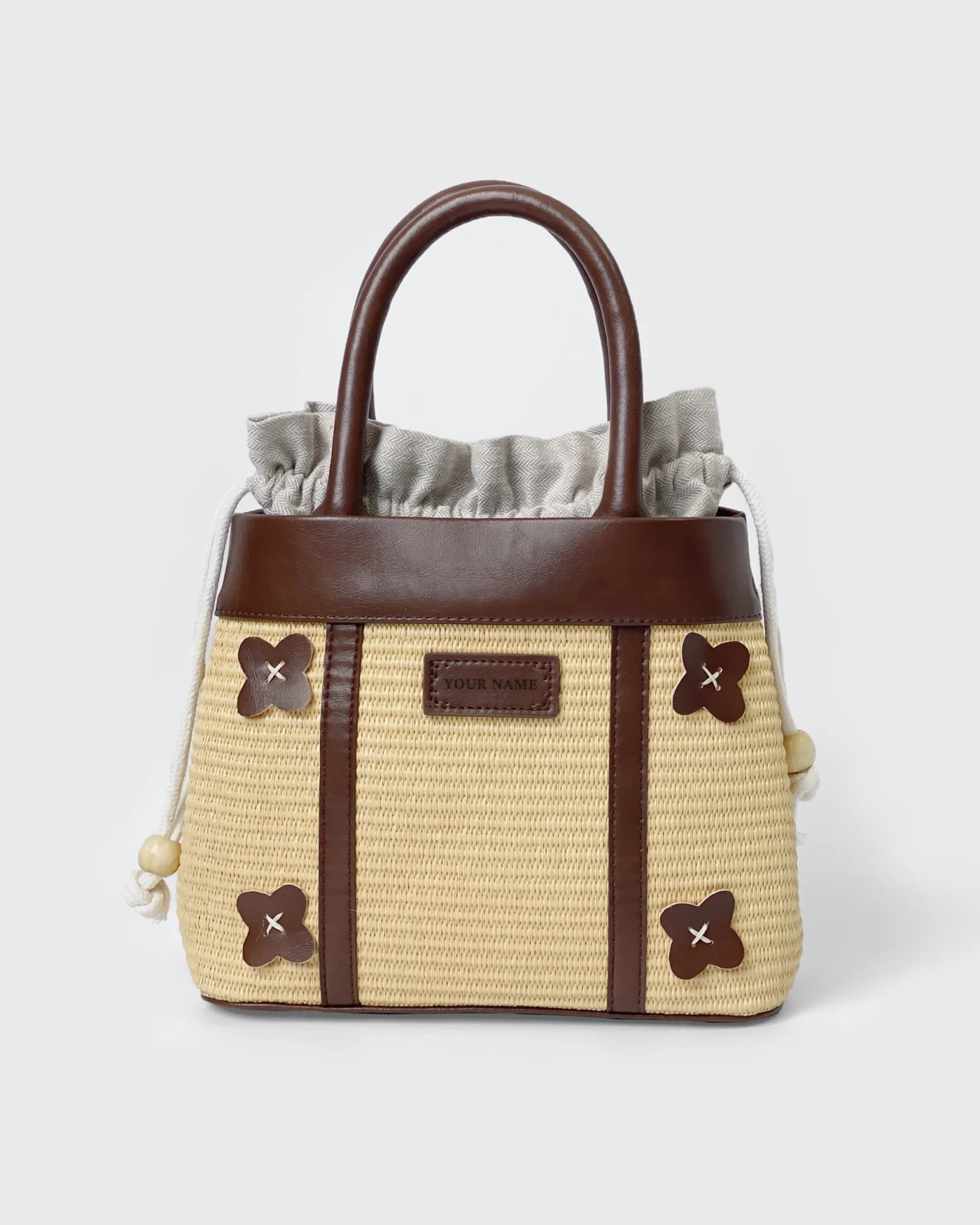 Elegant straw and leather handbag with floral accents and drawstring closure on display. Ideal for casual outings.