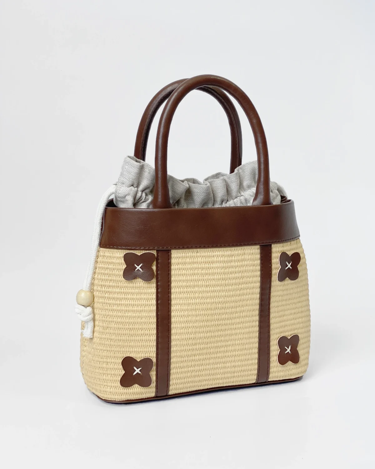 Elegant ROSIE HONG straw bag with brown leather details and fabric lining, featuring unique cross-stitch accents.
