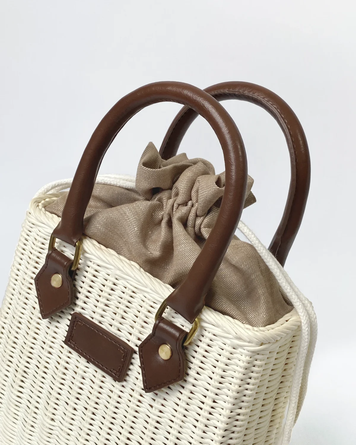 Stylish woven handbag with leather handles and drawstring closure, perfect for casual outings and beach trips.