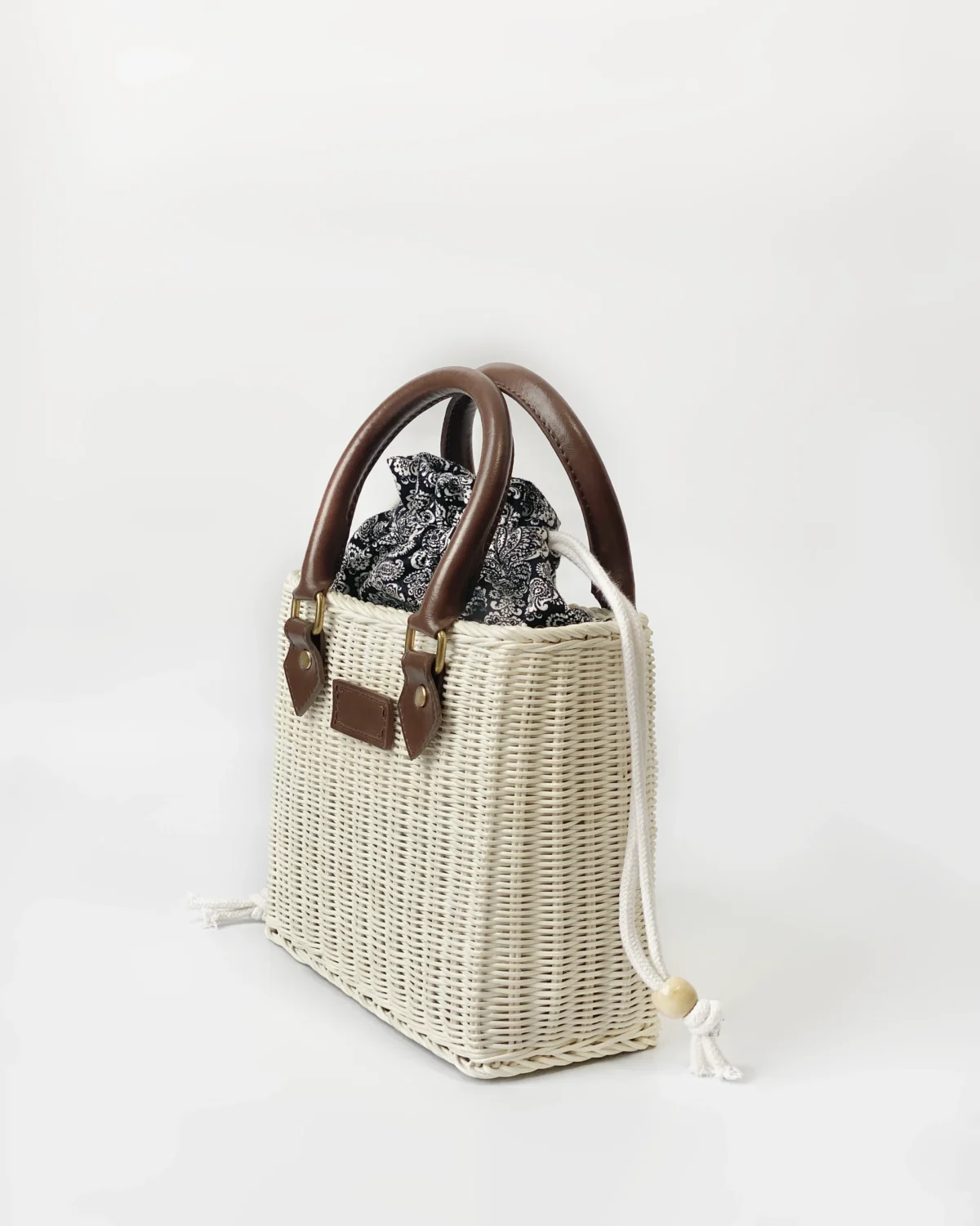 Wicker handbag with leather straps and floral fabric, ideal for summer fashion and casual outings.