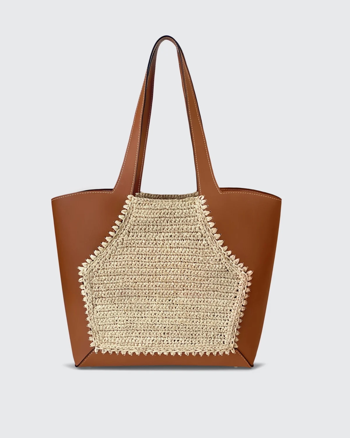 Brown vegan leather tote bag with woven straw panel, stylish and spacious for everyday use.