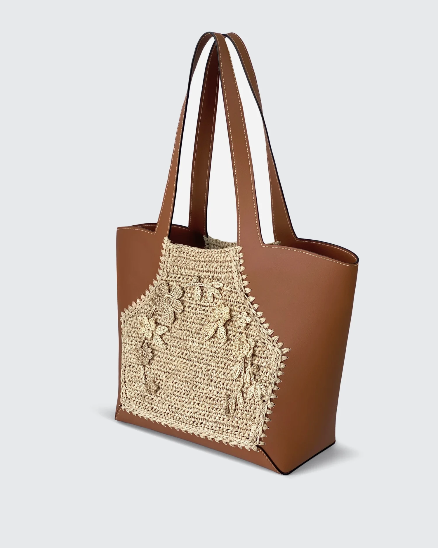 Brown vegan leather tote bag with intricate crochet floral design on one side, elegant and stylish accessory.