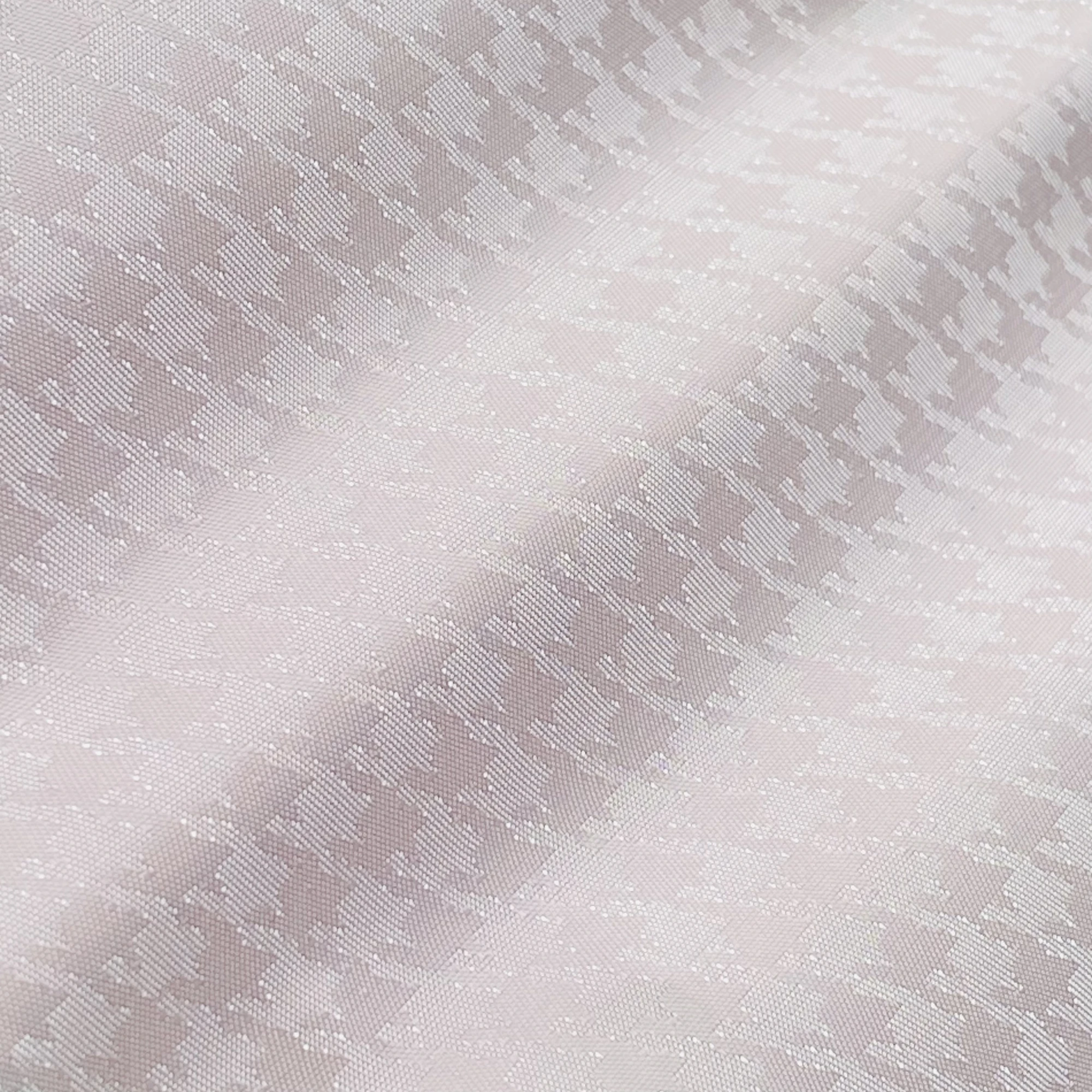 Close-up of a light pink houndstooth fabric pattern, showcasing its detailed texture and soft color.