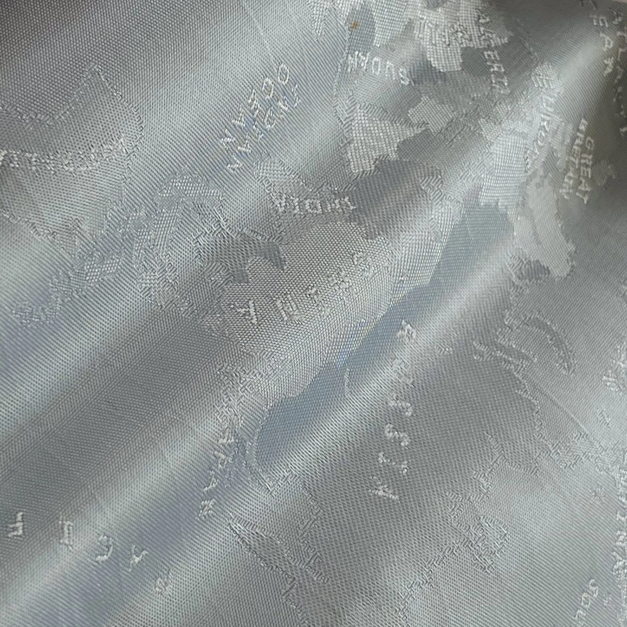 Close-up of textured fabric with an embossed world map showing continents in a metallic sheen.