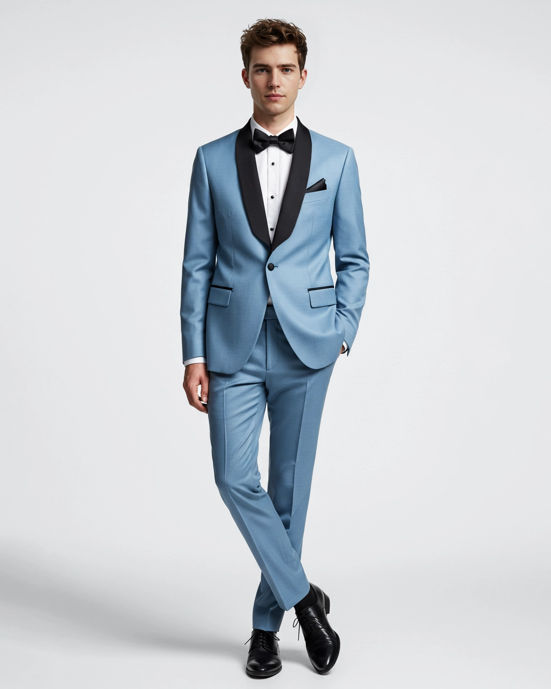 Man in light blue tuxedo with black lapels, white shirt, and bow tie standing confidently against a plain background.