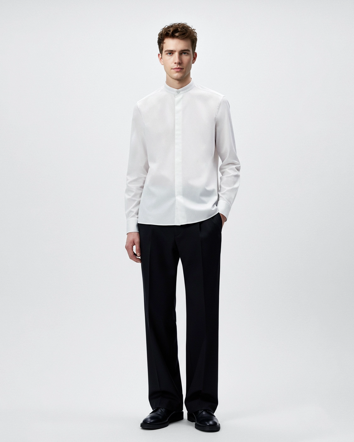 Man wearing a white mandarin collar shirt and black trousers, standing against a plain background.