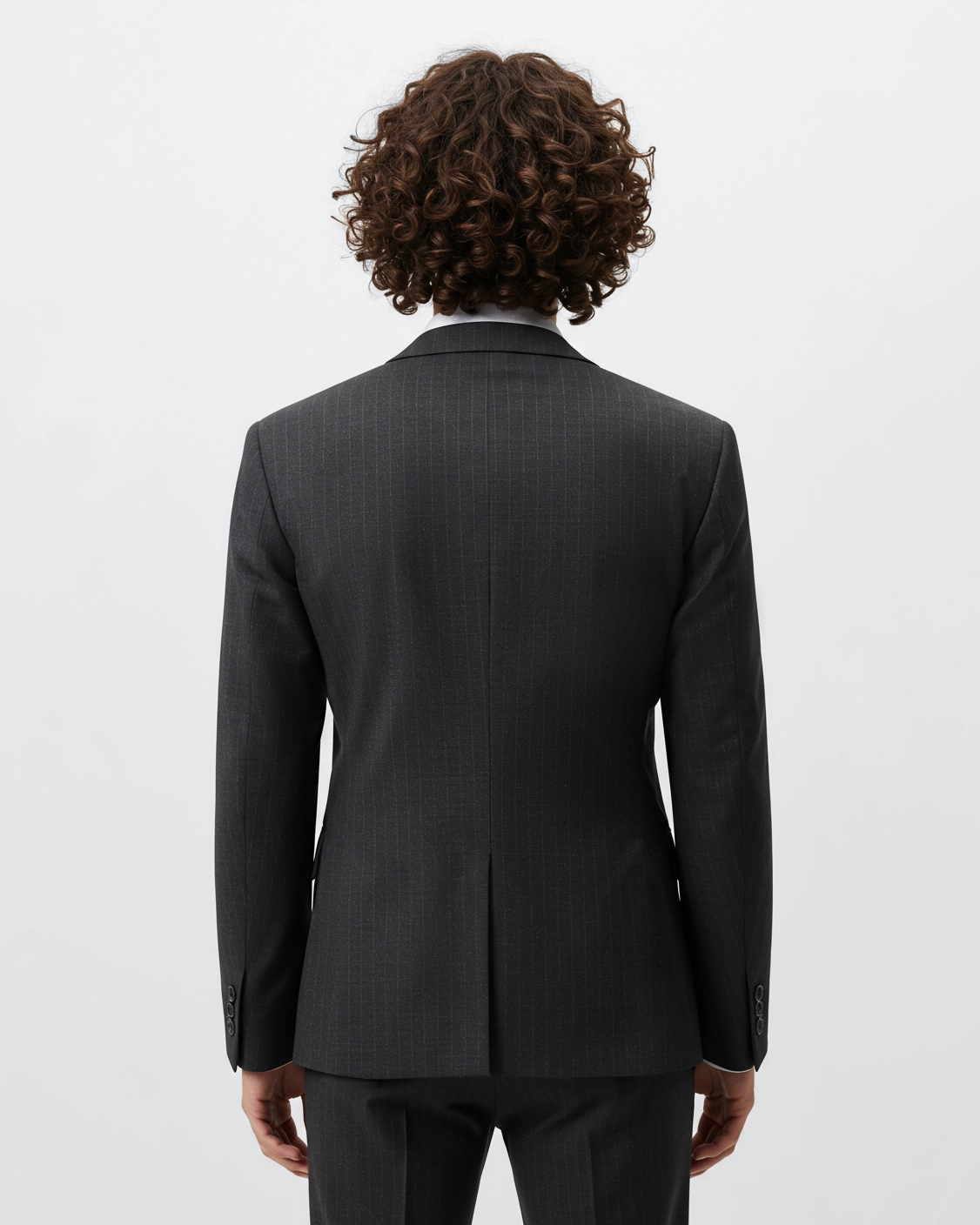 Back view of a person in a dark pinstripe suit with curly hair, showcasing the fit and style of the jacket.