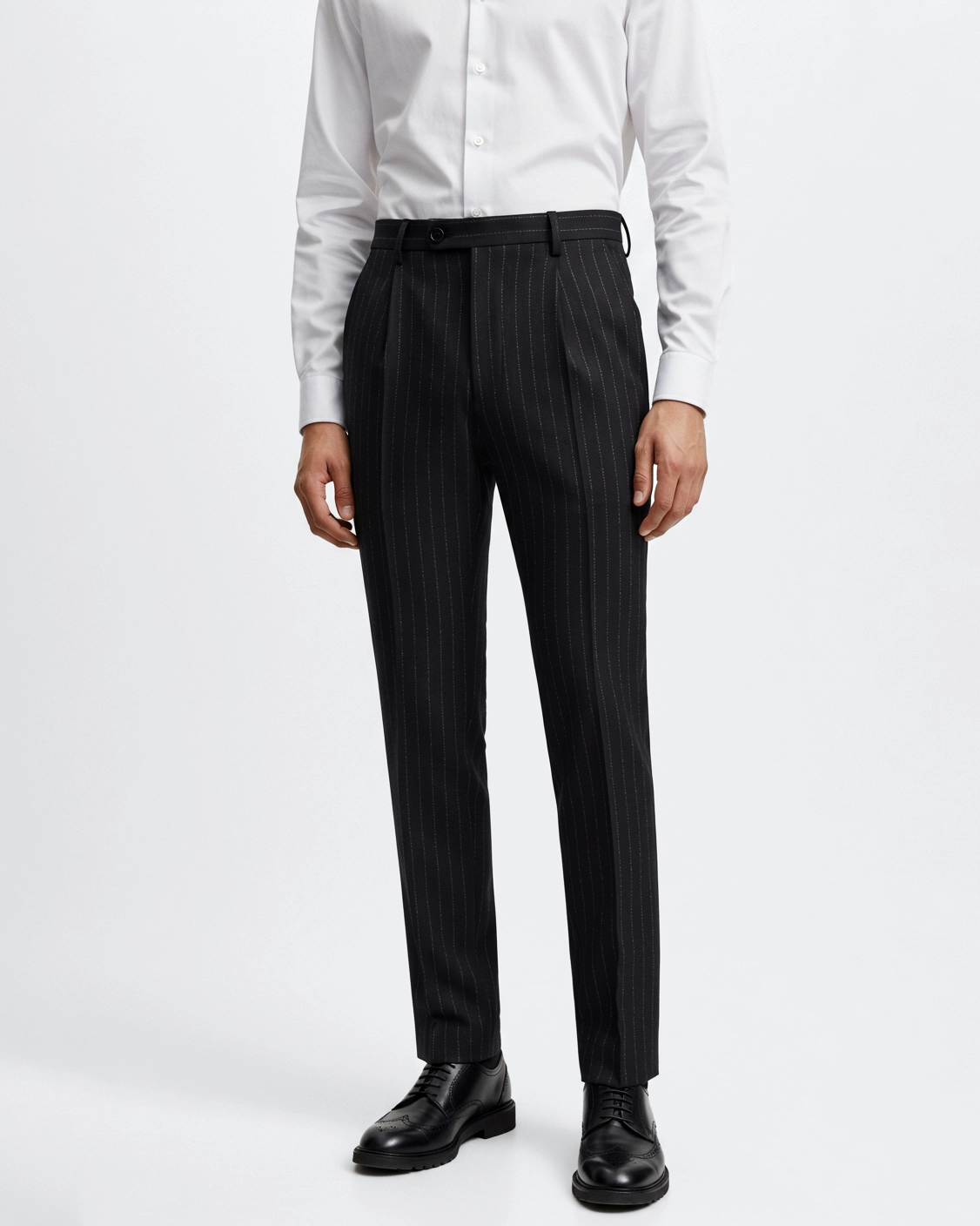 Man wearing black pinstripe pants, white shirt, and black dress shoes for a formal or business look.