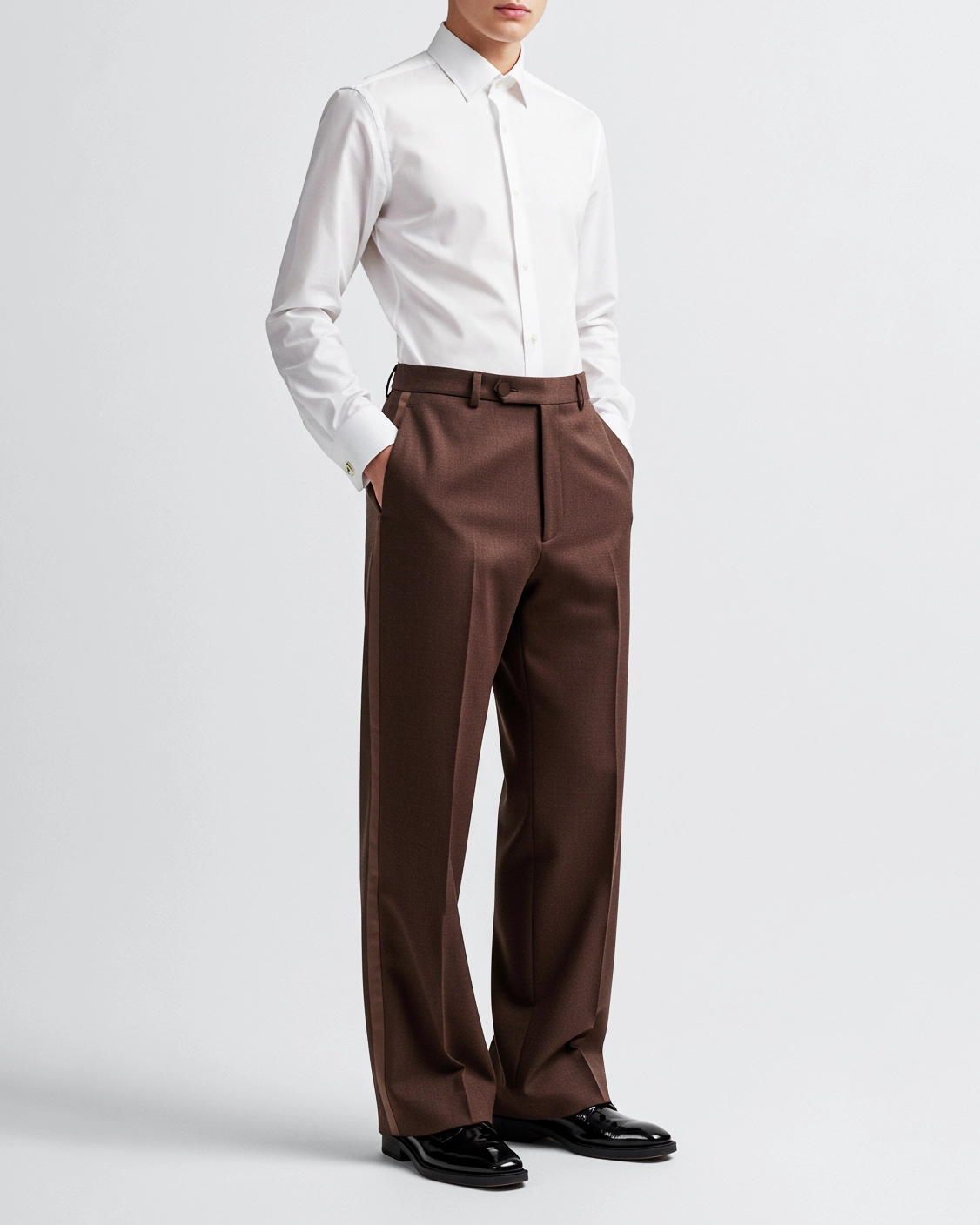 Man in white dress shirt with brown trousers and black shoes on a white background.