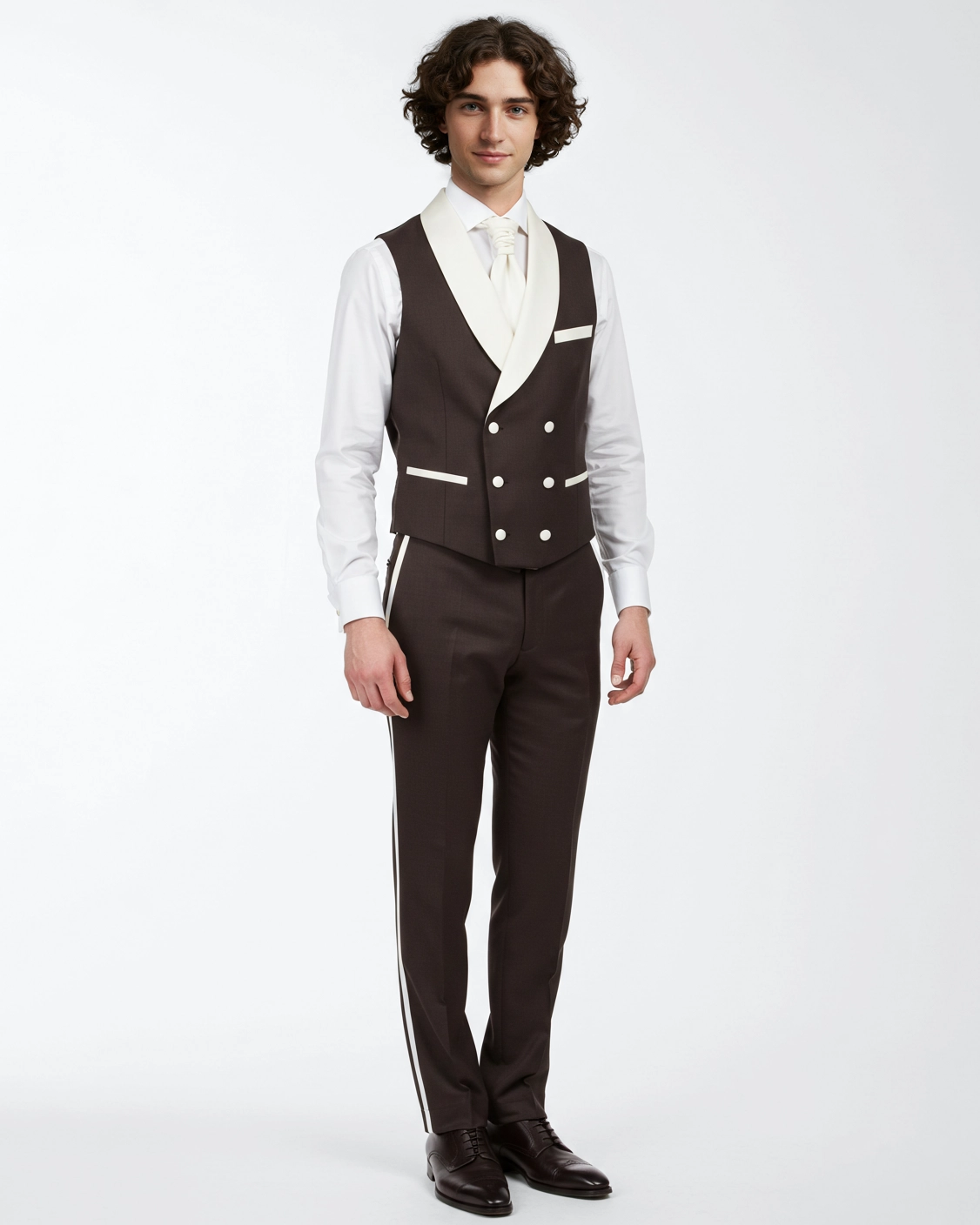 Man wearing a stylish brown suit with a white vest and tie, posing against a plain background.