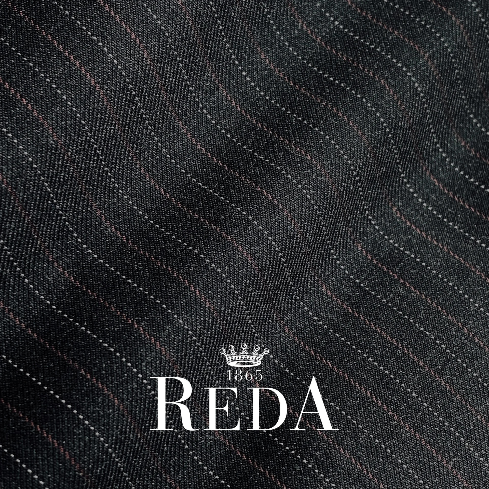 Close-up of dark pinstripe fabric with REDA 1865 logo, showcasing premium textile quality.