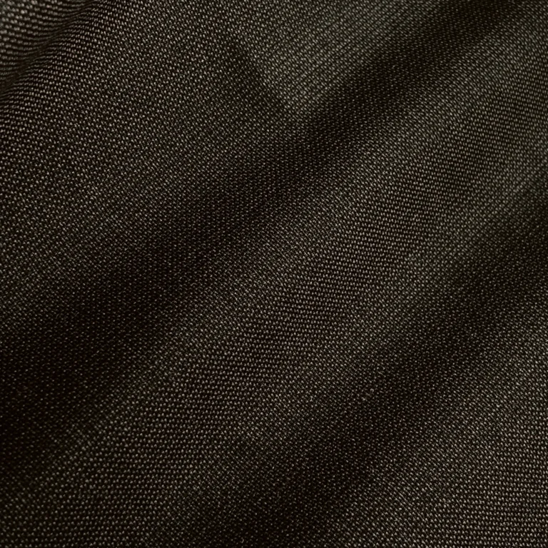 Close-up of dark, textured fabric with fine weaving, showcasing detailed textile quality for fashion and interior design.