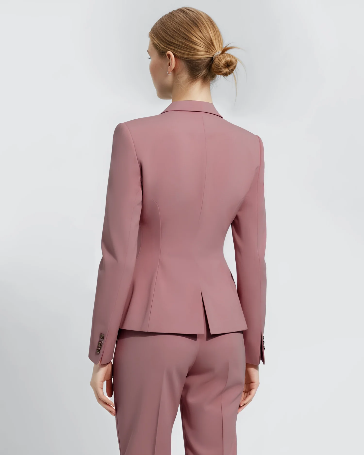 Woman in a pink tailored suit, photographed from behind, showcasing elegant professional attire.