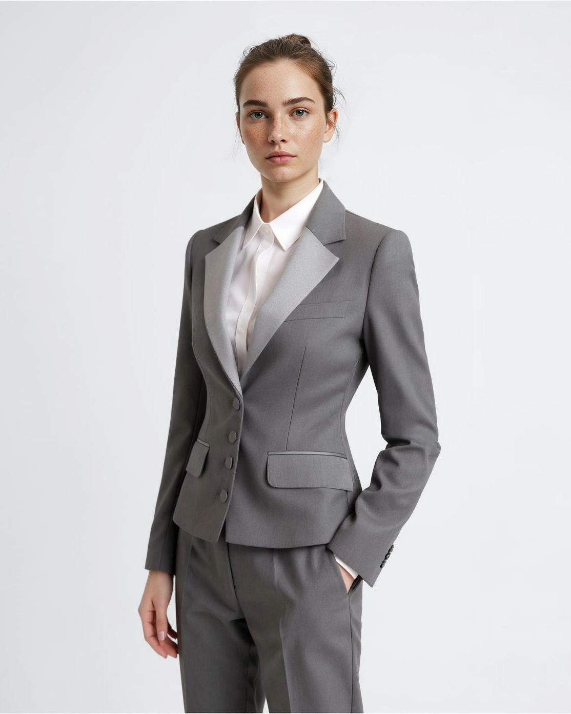 Business professional in a tailored grey suit, posing confidently against a neutral background. Office attire concept.