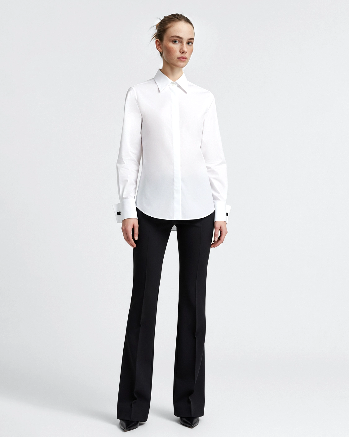 Woman wearing a white dress shirt and black pants, standing on a white background.