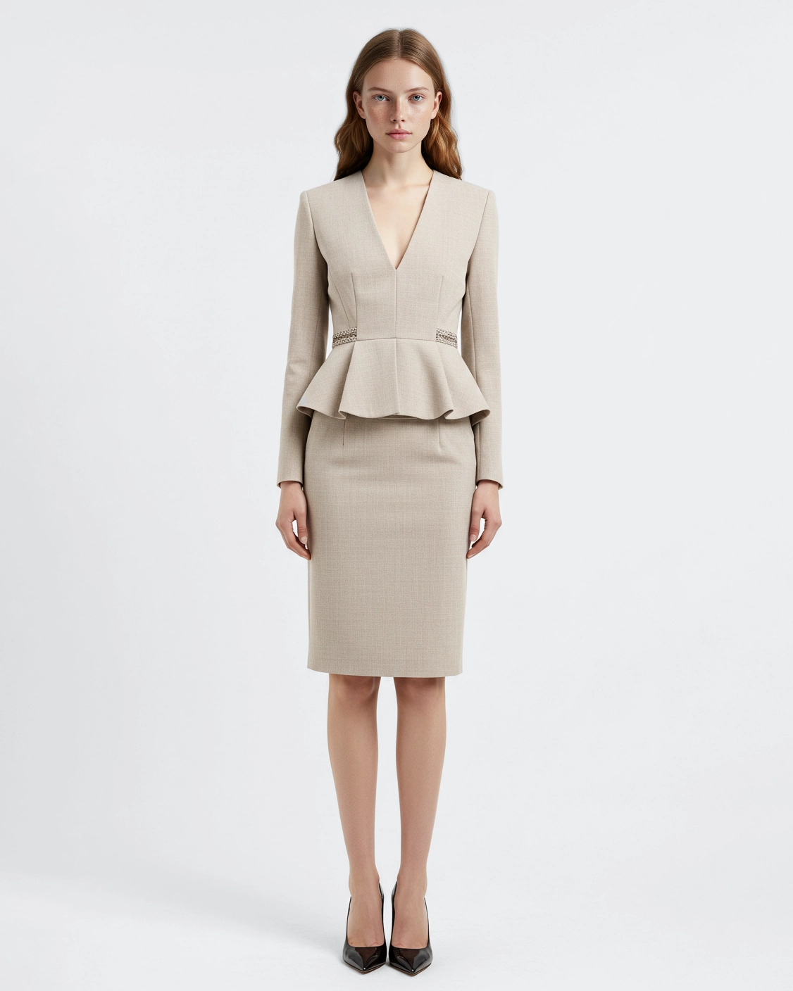 Woman wearing a beige peplum dress and black heels against a white background.