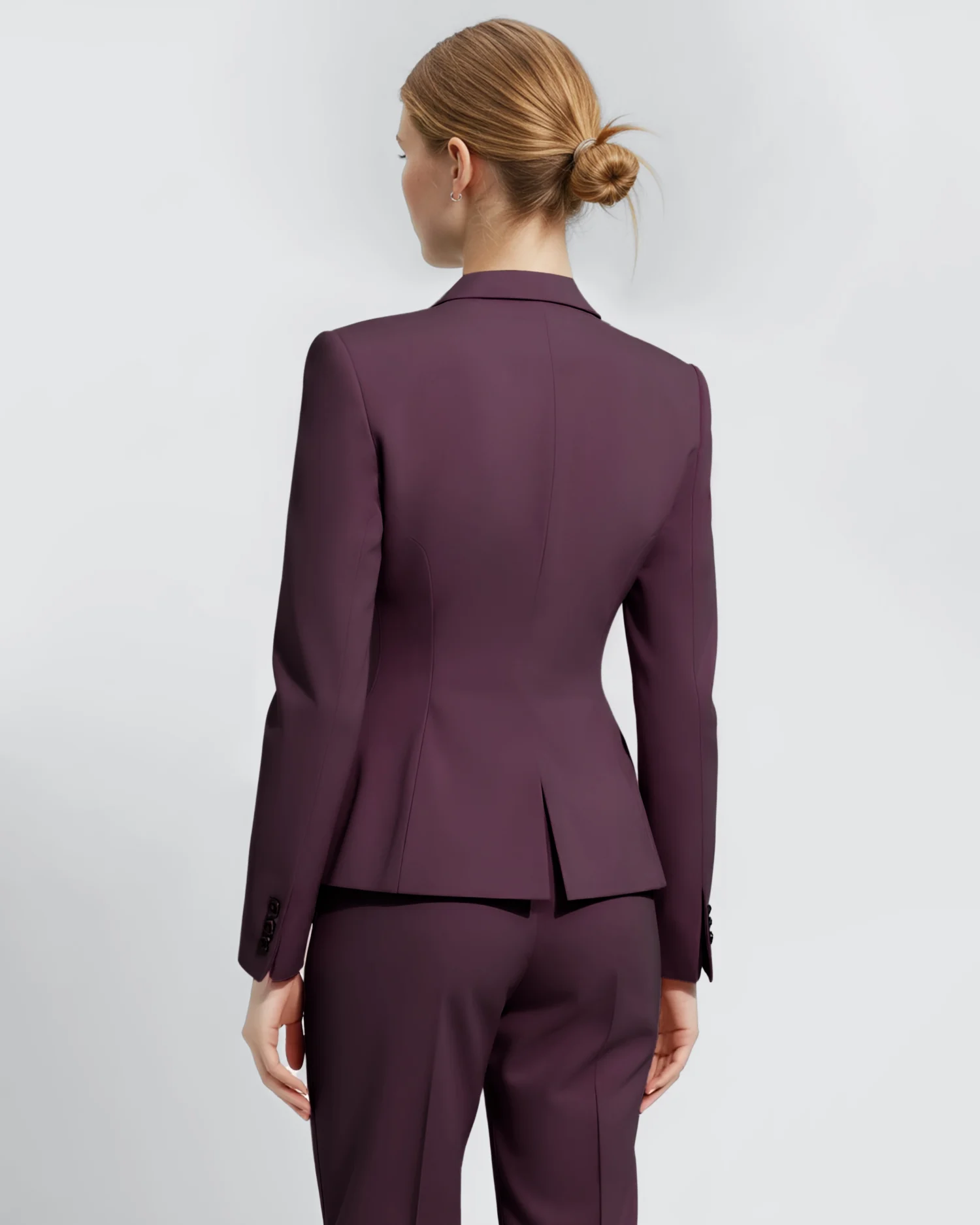 Woman wearing a stylish plum blazer and trousers, seen from the back, against a light background.