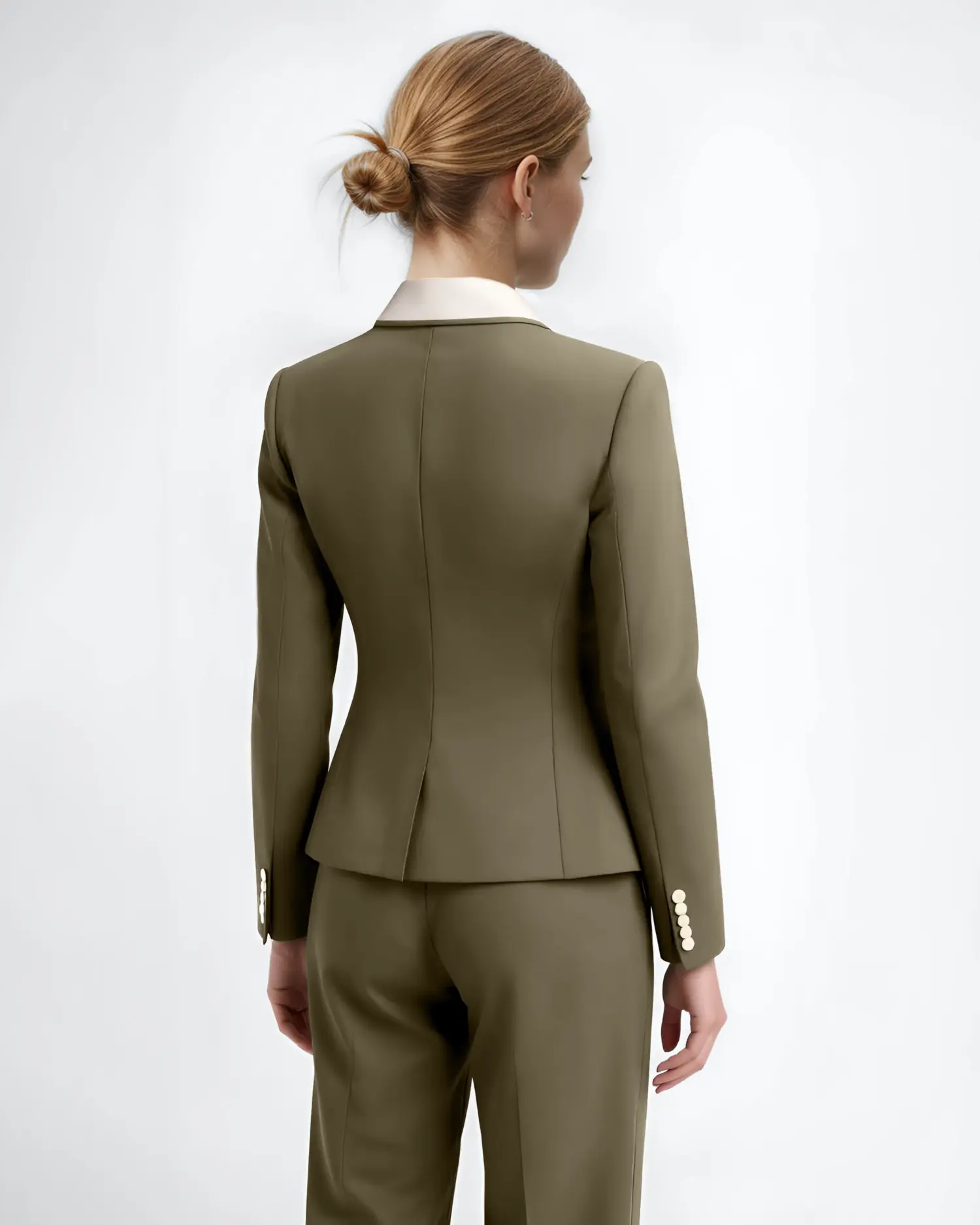 Woman in an olive green tailored suit with a white collar, seen from the back, against a light background.