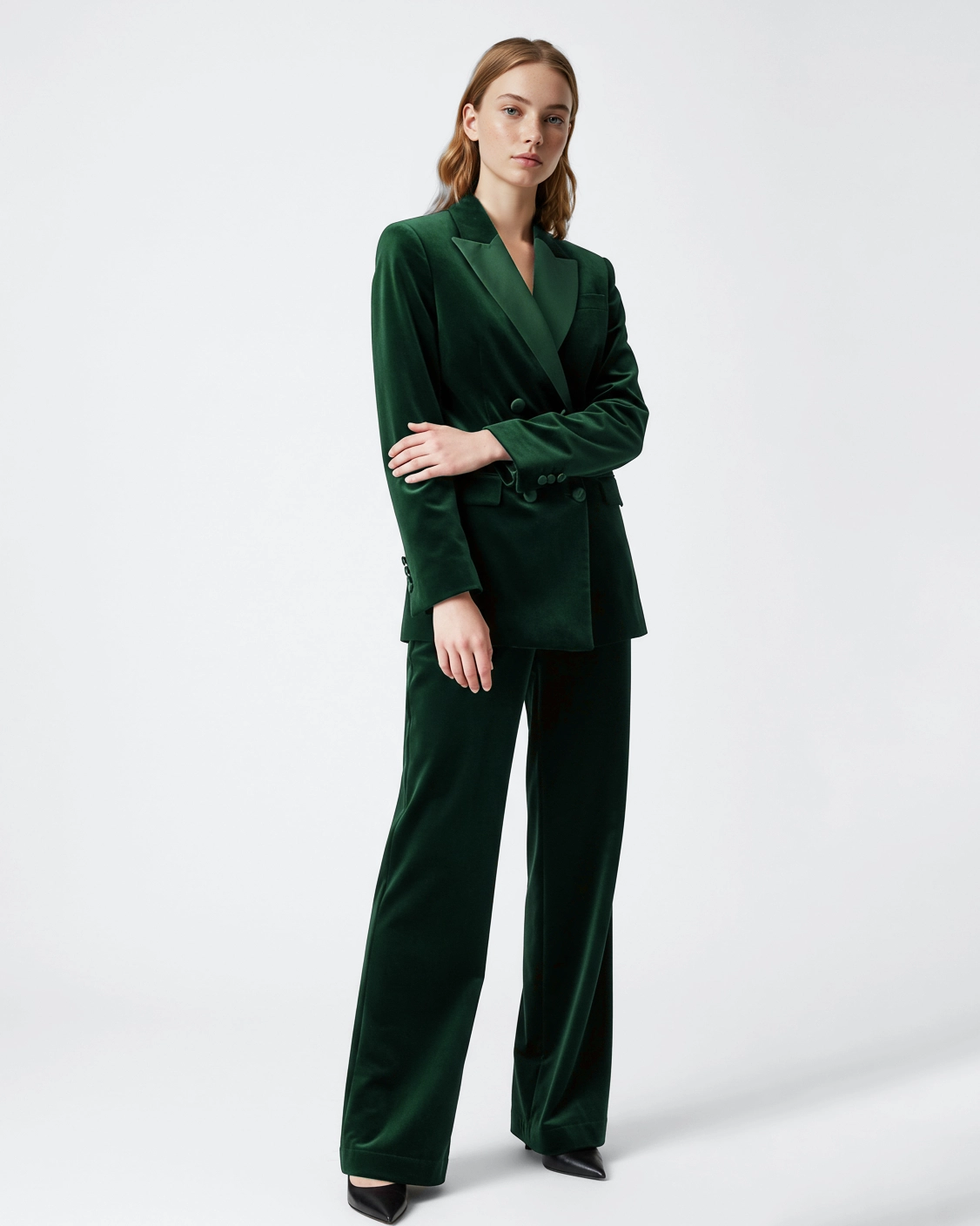 Woman in green velvet suit, posing with confidence against plain background. Fashion and style concept.