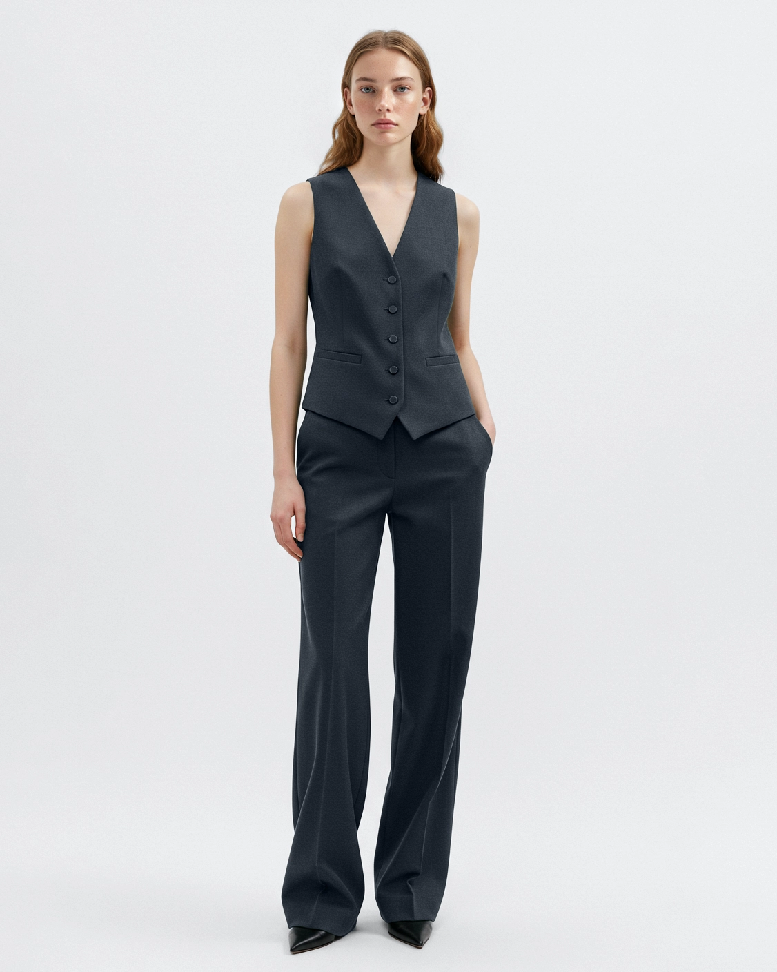 Person wearing a stylish dark gray vest and matching wide-leg pants, posing against a plain white background.