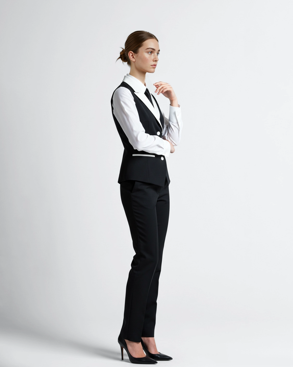 Woman in a business suit, standing with arms crossed, looking confident against a white background.