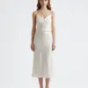 Woman in elegant ivory satin slip dress with thin straps, standing against a plain background.