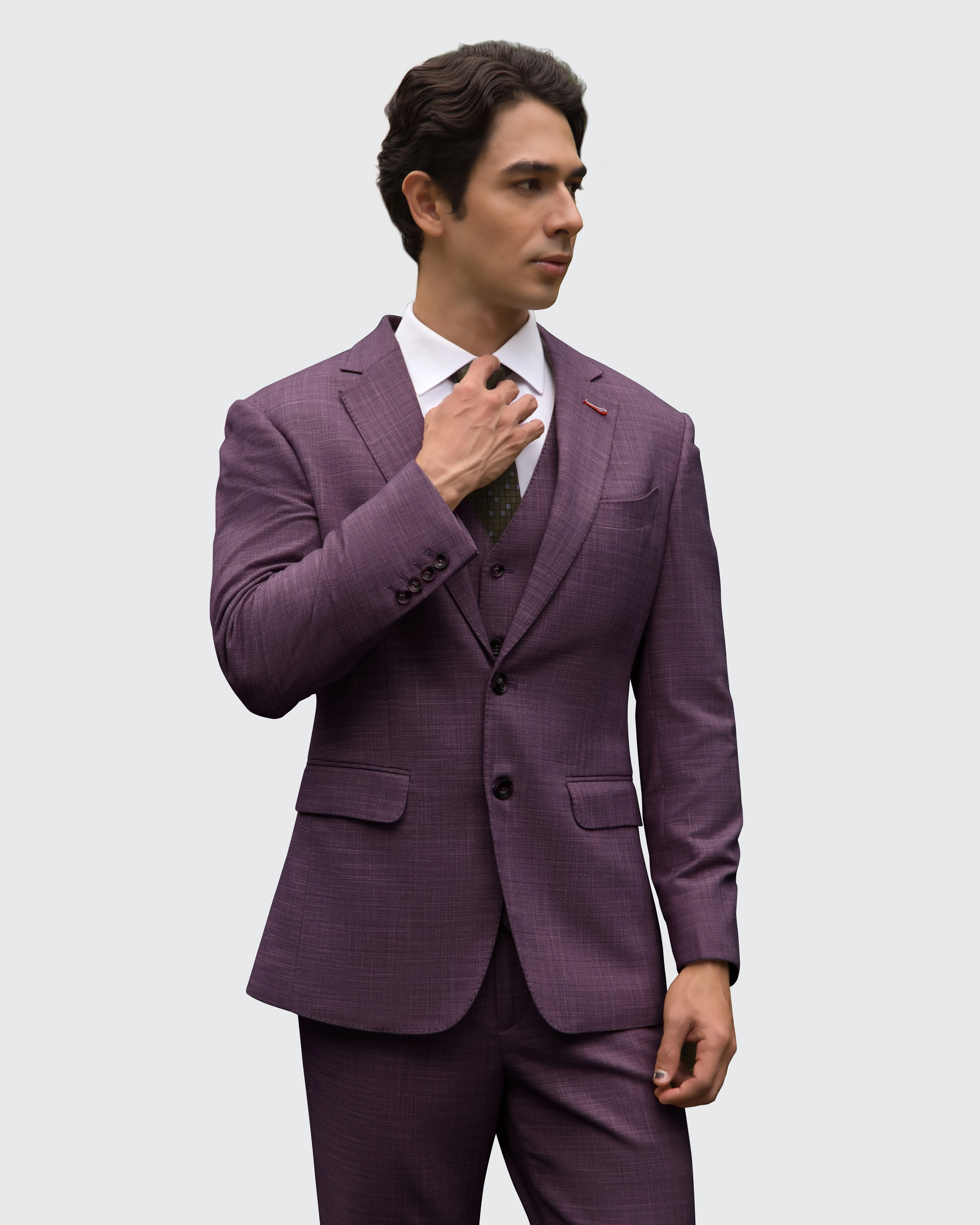 Man in a tailored purple suit adjusting his tie, demonstrating formal attire style on a neutral background.
