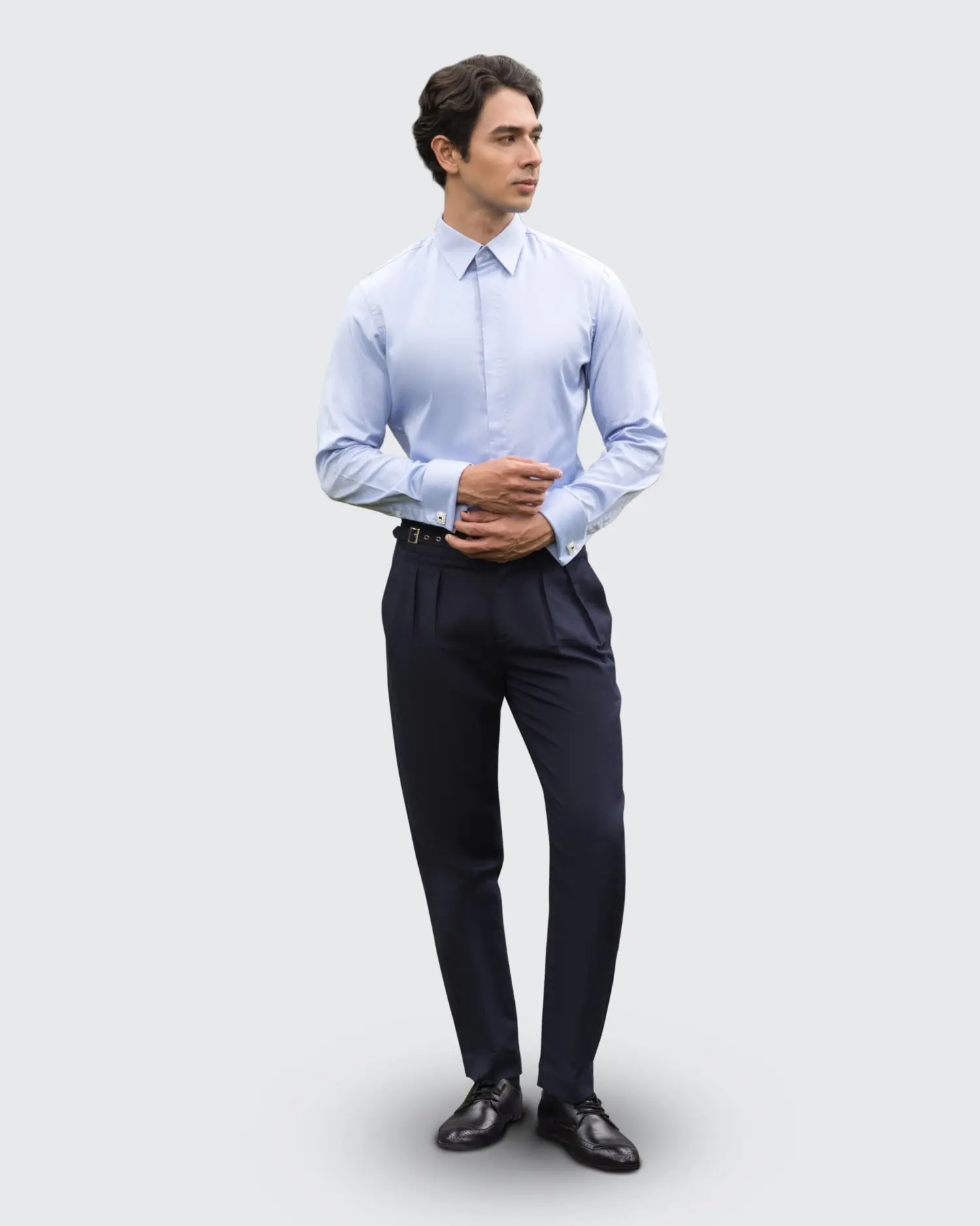 Man in formal attire wearing a light blue shirt and navy pants, standing confidently against a neutral background.