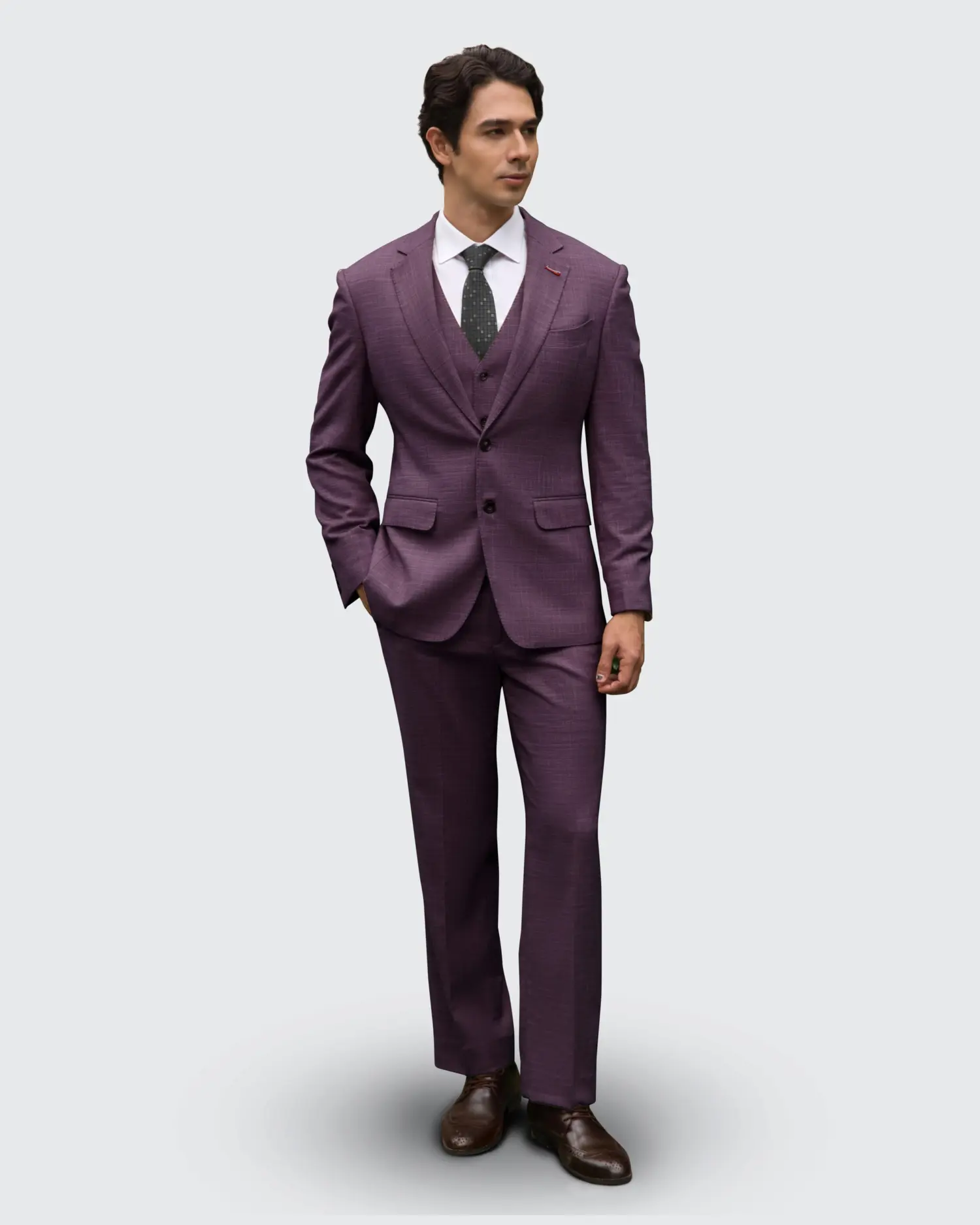 Man in a stylish purple suit with a white shirt and dark tie, standing confidently against a plain background.