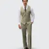 Man in elegant olive suit with vest and tie, standing confidently against plain background.