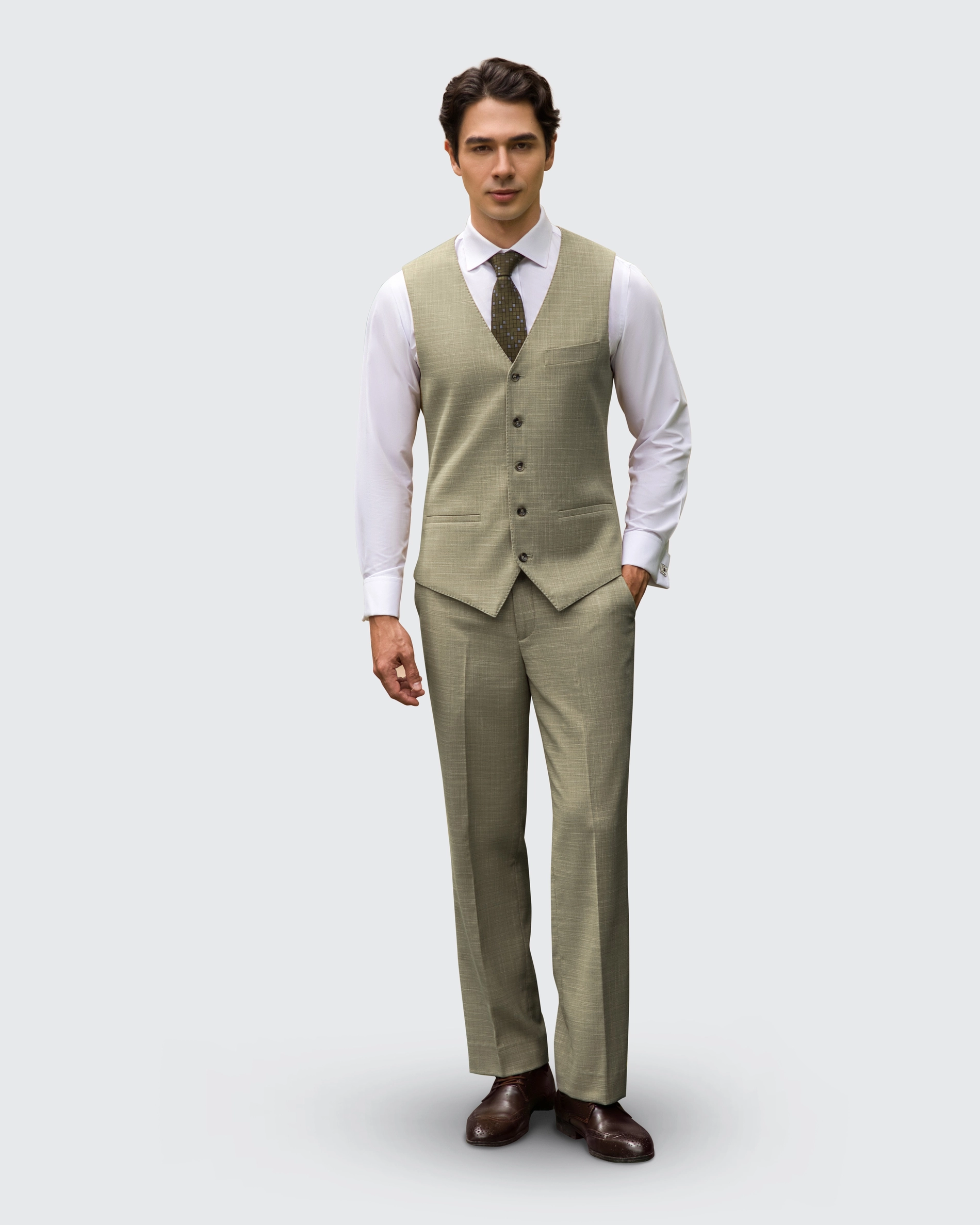 Man in elegant olive suit with vest and tie, standing confidently against plain background.