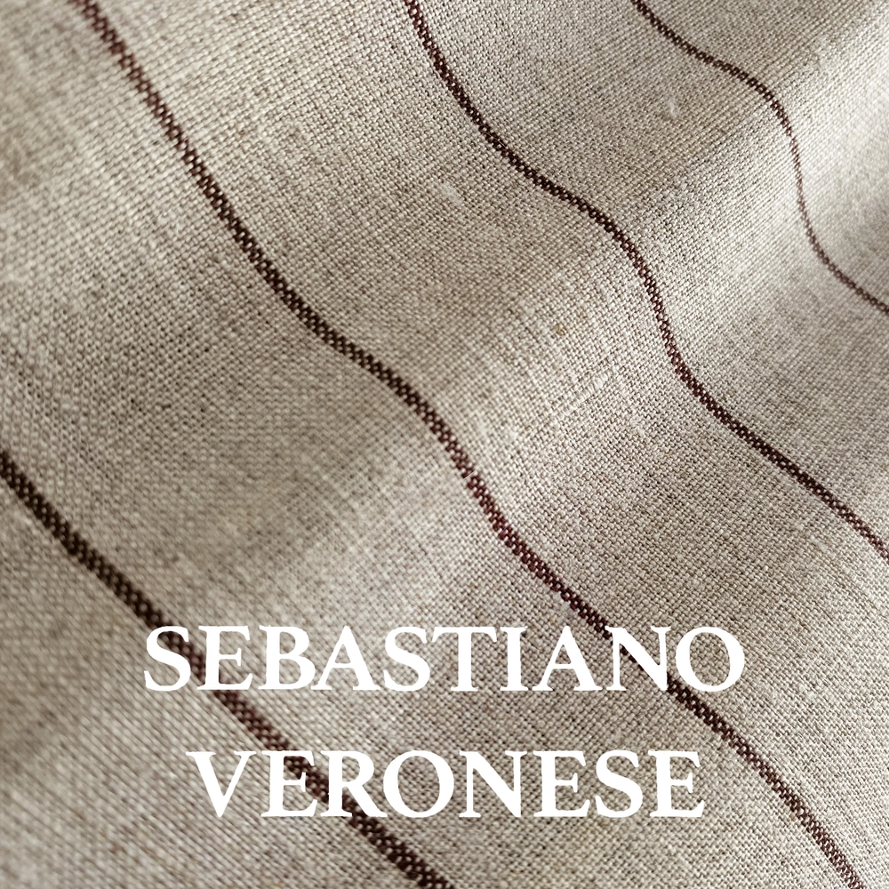 Close-up of textured fabric with brown stripes and the text Sebastiano Veronese on a wavy beige background.