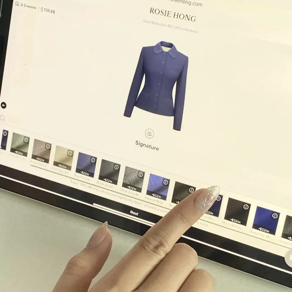 Person selecting blue jacket on online fashion store via tablet.
