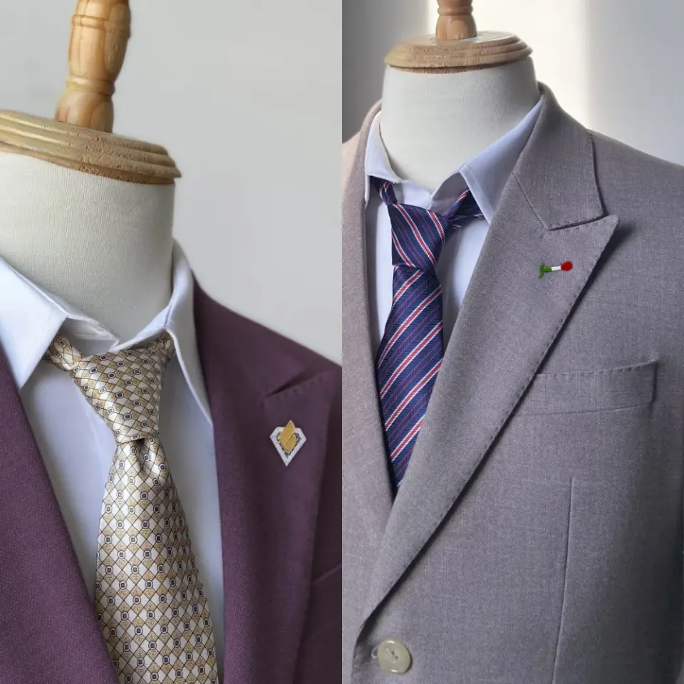 Two mannequin torsos in stylish suits and ties, showcasing elegant formal wear with lapel pins.