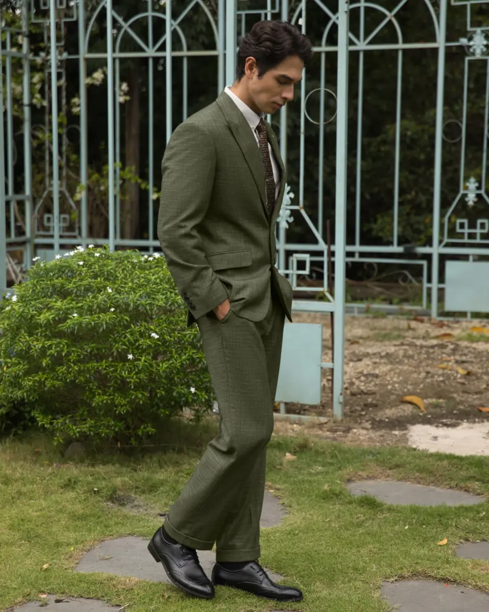 a man wears a men two-piece suit stands outdoors near decorative iron fence.