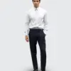 Man wearing a white dress shirt and navy trousers, standing against a light background.