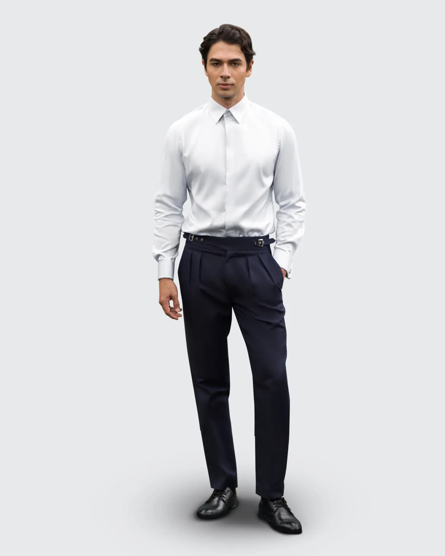 Man wearing a white dress shirt and navy trousers, standing against a light background.