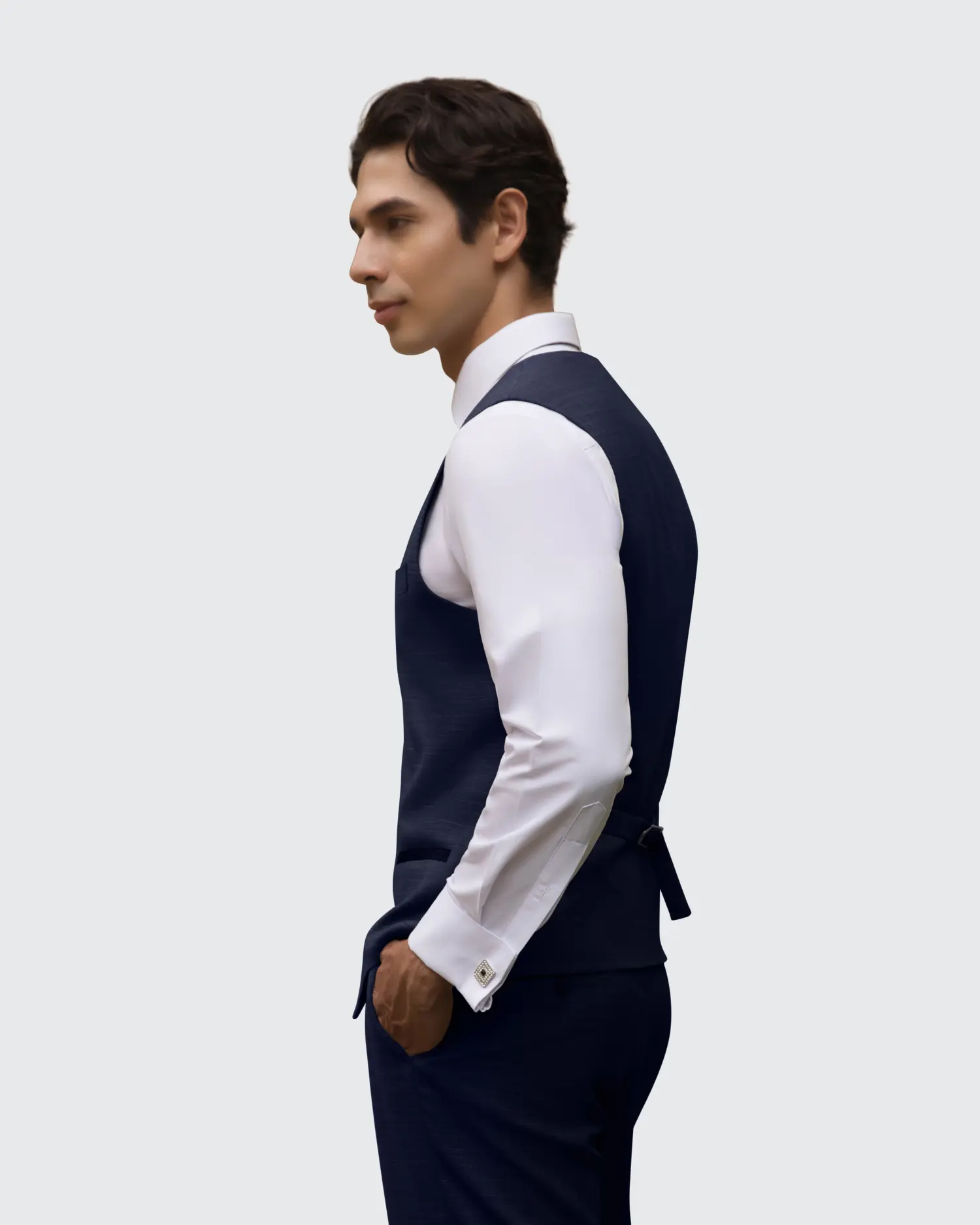 Man in navy suit and white shirt, posing confidently, side view, isolated on light background.