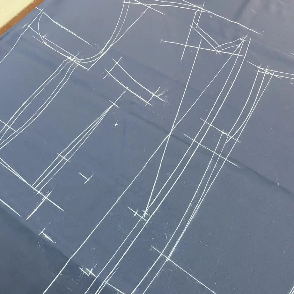 Tailoring pattern drawn on dark fabric with white chalk lines, perfect for dressmaking and sewing projects.