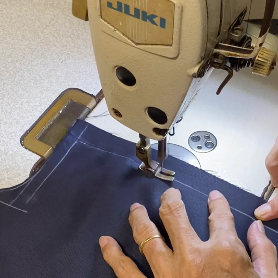 Close-up of a tailor sewing fabric on a machine, highlighting the handmade precision of bespoke tailoring.