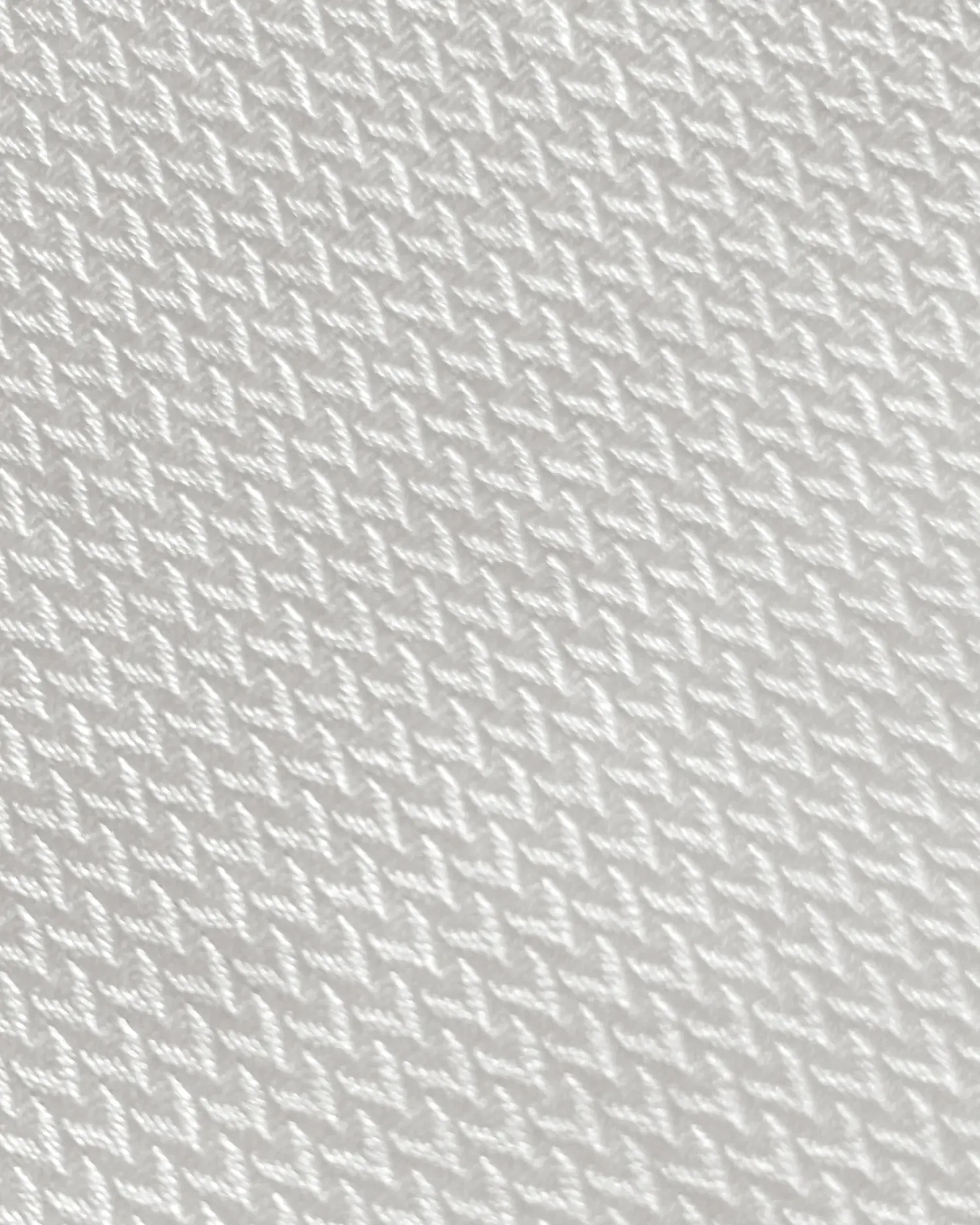 Close-up of white textured fabric with a herringbone pattern, showing intricate weaving details.