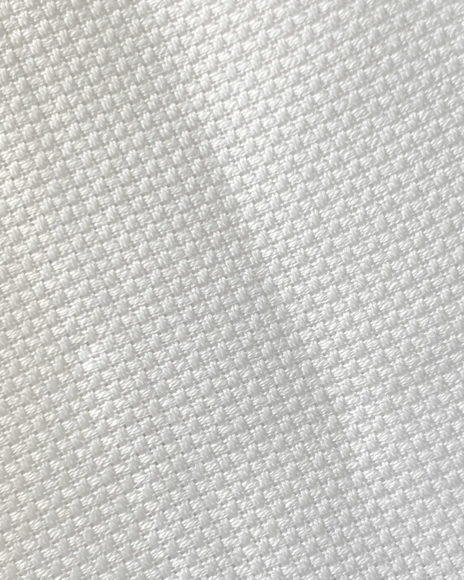 Close-up of white textured fabric with a woven pattern, ideal for upholstery or interior design projects.