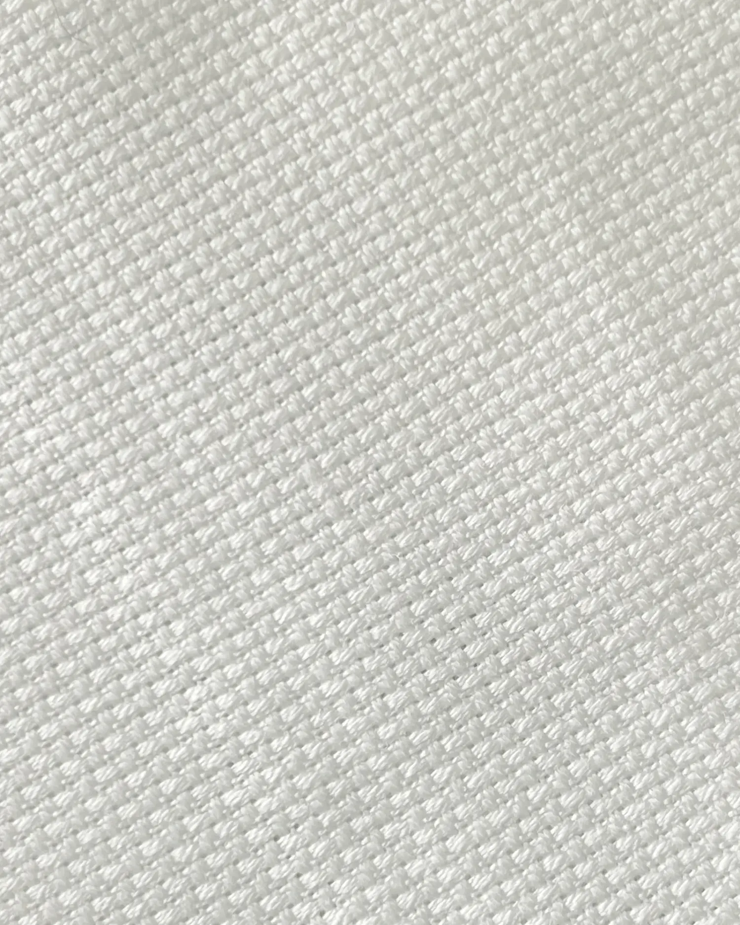 Close-up of white woven fabric texture, showcasing its detailed pattern and soft appearance.